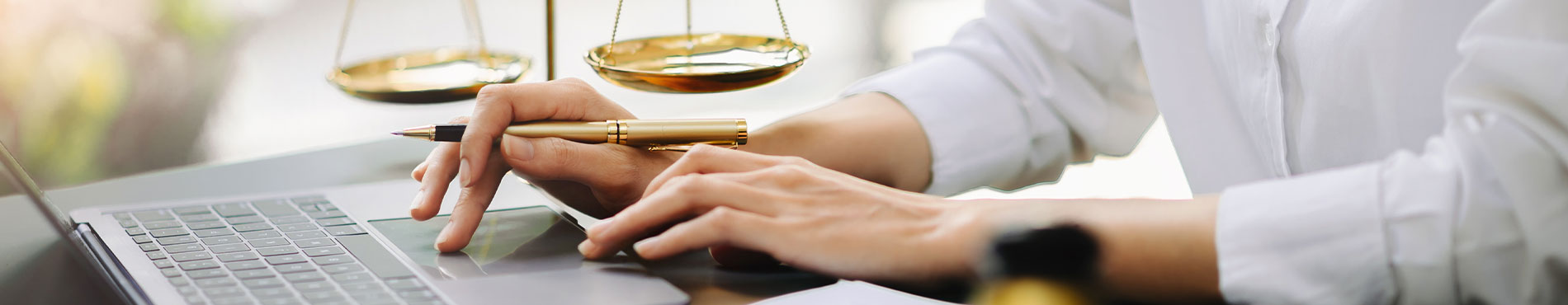 Eine Person am Laptop, umgeben von Justizsymbolen, vermittelt Professionalität und Konzentration.