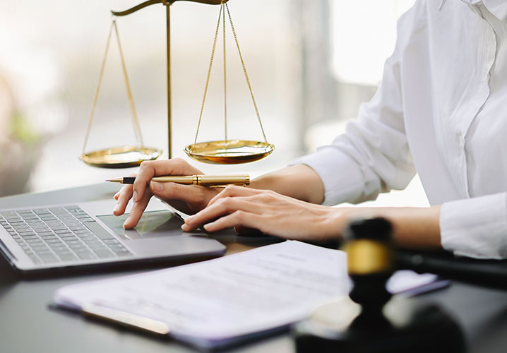 Eine Person am Laptop, umgeben von Justizsymbolen, vermittelt Professionalität und Konzentration.