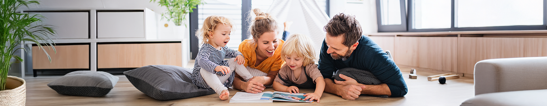 privater Versicherungsbereich: eine Familie liest zusammen auf dem Boden