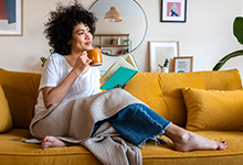  privater Versicherungsbereich: eine Frau liest auf einer gelben Couch ein Buch
