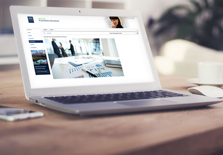 Ein Laptop auf einem Holztisch zeigt eine das Kundenportal, Atmosphäre von geschäftlichem Austausch.